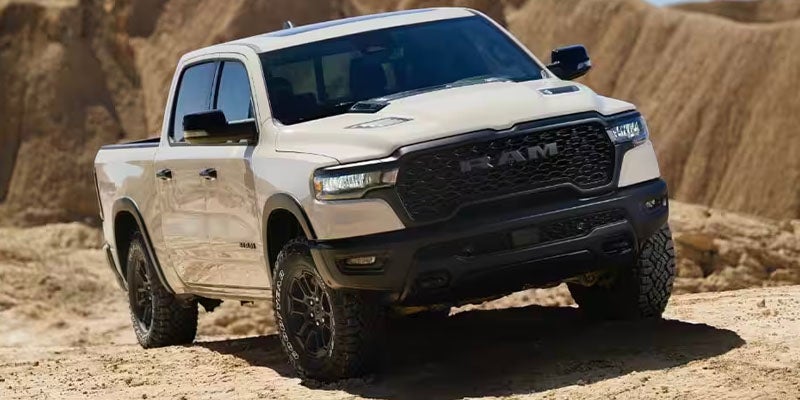 A white RAM 1500 Rebel truck driving on a dirt trail