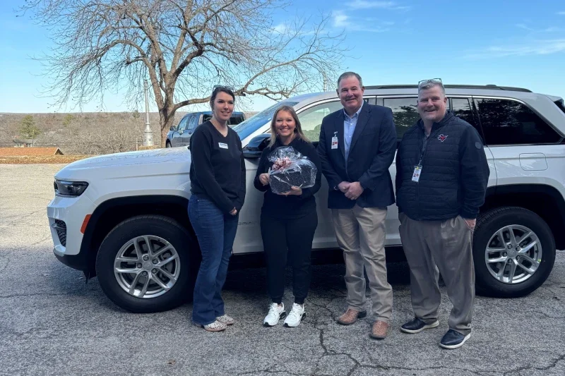 Group of people standing by white SUV and one woman is having gifts in hand.