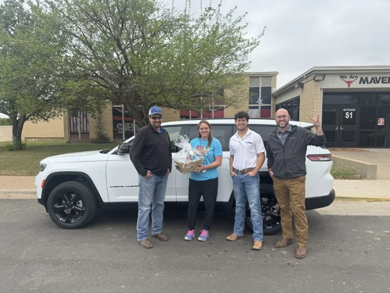 Group of people posing in front of SUV.
